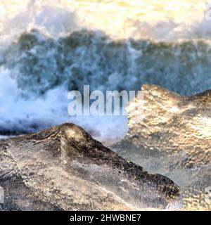 Ghiaccioli e onde che si infrangono alla luce del sole dorata di prima mattina. Diamond Beach, Islanda. Il mare lava grandi pezzi di ghiaccio glaciale fino alla spiaggia, fr Foto Stock