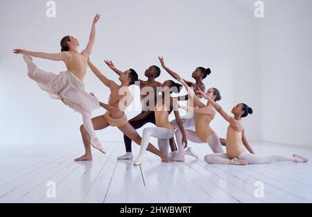 Creare bellezza. Girato di un gruppo di ballerini che praticano una routine in uno studio di danza. Foto Stock