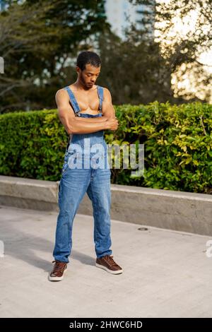 Bel giovane uomo nero in posa in tute nel parco Foto Stock