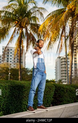 Foto di un bel modello maschile afroamericano in parco con palme sullo sfondo Foto Stock
