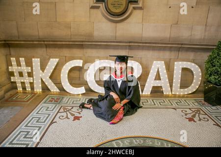 Una donna asiatica graziosa si pone per le fotografie alla sua cerimonia di laurea. Questo evento formale in cui le lauree (prima) si trasformano in laureati Foto Stock