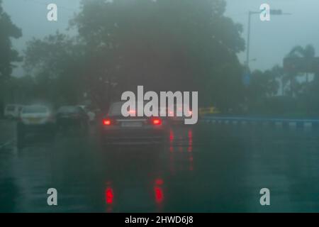 Immagine sfocata di Kolkata, Bengala Occidentale, India. Immagine scattata attraverso gocce di pioggia che cadono su vetro bagnato, sfocature astratte del traffico - immagine monsone di Kolkata. Foto Stock