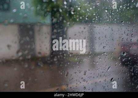 Immagine scattata attraverso gocce di pioggia che cadono su vetro bagnato, sfocature astratte del traffico - monsone immagine di riserva della città di Kolkata (ex Calcutta), Bengala Occidentale, Foto Stock