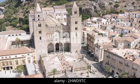 Splendida vista sulla vecchia cattedrale grigia circondata da edifici con una grande scogliera di montagna sullo sfondo in una calda giornata estiva. Splendido arco antico Foto Stock