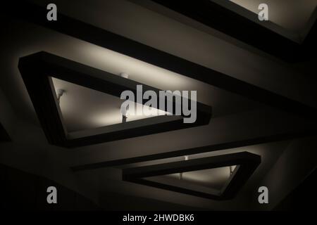 Lampada triangolare sul soffitto. Dettagli interni. Luce nella hall. Design dell'apparecchiatura di illuminazione. Foto Stock