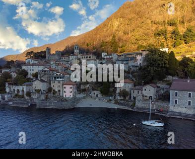 VISTA AEREA. Foto panoramica, vista da cartolina dal lago di un piccolo borgo antico in Lombardia, Lago di Como, Italia Foto Stock