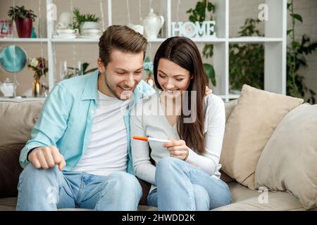 Donna che sorprende suo marito con test di gravidanza positivo, Foto Stock