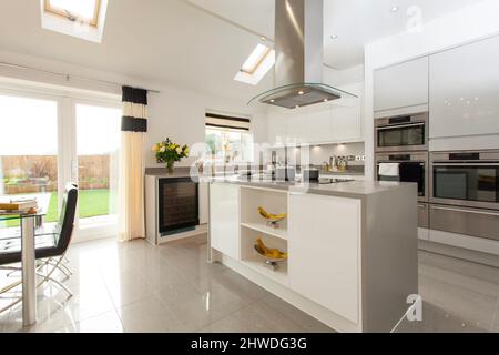 Cucina con angolo cottura centrale, piano cottura a induzione e cappa di cottura in showhome moderno. Foto Stock