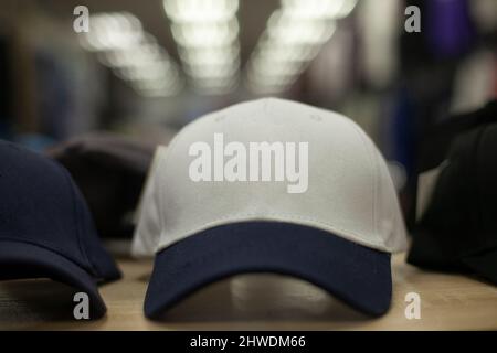 Cappuccio bianco con visiera blu. Cappello per l'estate. Vendita di abiti in negozio. Dettagli degli articoli in vetrina. Foto Stock