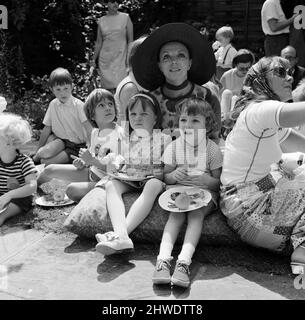 L'attore Michael Crawford tiene un barbecue nel giardino della sua casa a Wimbledon. Stelle e i loro figli vengono, è in aiuto della Wimbledon Park Nursery School. Nella foto, l'attrice Joan Collins con i suoi 2 figli, ha lasciato Tara 6 anni e Sacha 4 anni hanno pranzo sull'erba. Wimbledon, Londra. 12th luglio 1970. Foto Stock