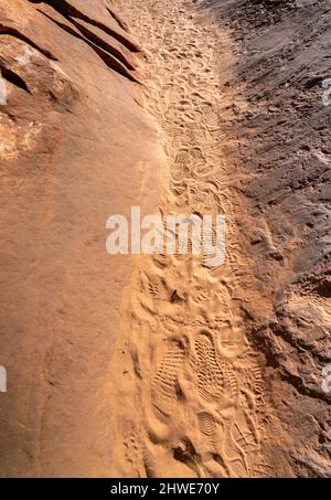 Vista del percorso stretto tra rocce grandi con stampe di scarpe sulla sabbia Foto Stock