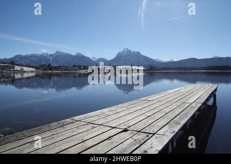 Hopfensee nella regione di Allgäu, Baviera, Germania. Vista sul Lago Hopfensee con riflessi e sfondo di montagna Foto Stock