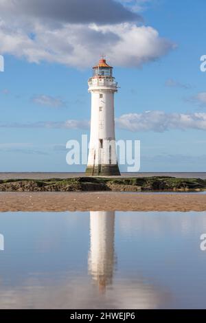 Il faro di New Brighton si riflette in una piscina d'acqua mentre la marea si estende nel marzo 2022 sulla costa del Wirral. Foto Stock