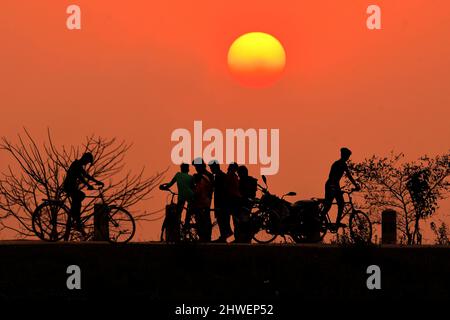 Nagaon, India. 5th Mar 2022. La gente è vista in silhouette durante il tramonto nel distretto di Nagaon dello stato nordorientale dell'India di Assam, 5 marzo 2022. Credit: Str/Xinhua/Alamy Live News Foto Stock