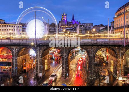 Vista della Cattedrale di Notre-Dame e del Grand Pont a Losanna con il mercato di Natale sotto e dietro il ponte. La ruota panoramica è una tempesta recente Foto Stock