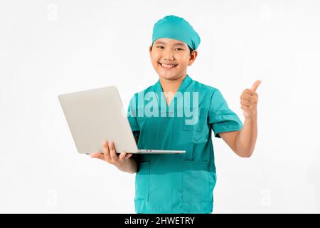 Ritratto di giovane asiatico vestito ragazzo per essere medico, tenendo notebook isolato su sfondo bianco, concetto di istruzione Foto Stock