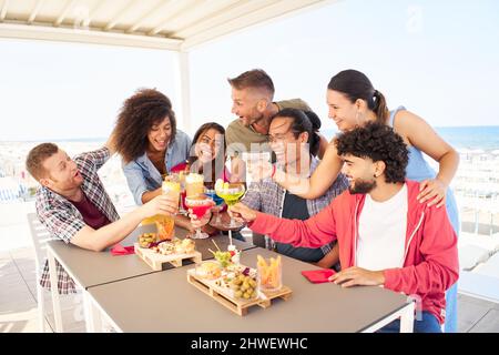 Multirazziale giovani amici divertirsi insieme tostando cocktail sul tetto. Concetto di stile di vita della comunità sociale Foto Stock
