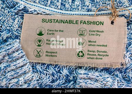 etichetta di moda sostenibile su jumper di lana con icone e testo di cura, consumismo etico Foto Stock