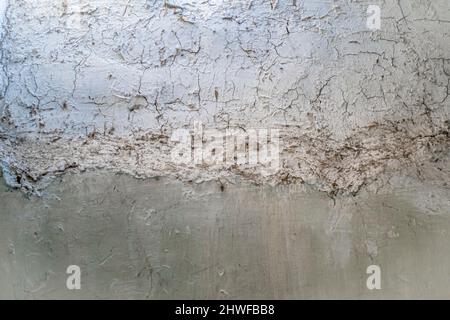 Vernice pallida incrinata su una vecchia parete di cemento con vernice intemperie Foto Stock