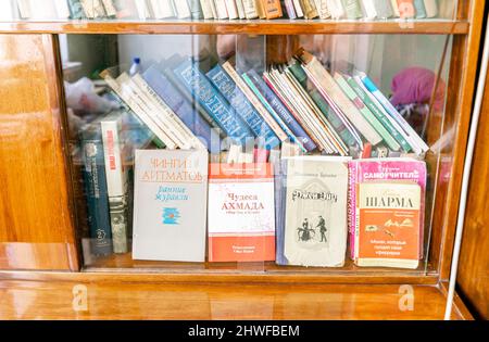 Vecchia libreria sovietica in vetro, tipica delle famiglie sovietiche. In confezione con libri impilati. Foto Stock