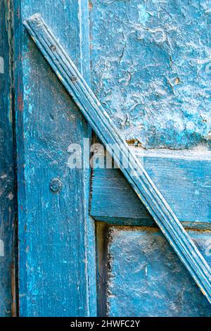 Vernice blu sbucciata su una vecchia porta di legno con vernice intemperie Foto Stock