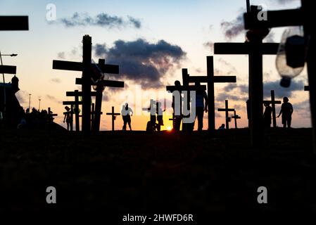 Silhouette di persone e croci fissate a terra in onore di quelli uccisi dal covid-19. Tramonto a Salva Foto Stock