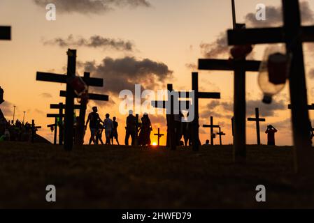 Silhouette di persone e croci fissate a terra in onore di quelli uccisi dal covid-19. Tramonto a Salva Foto Stock