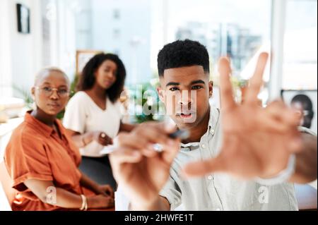 Concentrato sul fare i grandi progetti funzionare. POV colpo di un giovane uomo d'affari che tiene un marcatore mentre dà una presentazione in un ufficio. Foto Stock