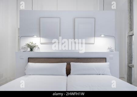 Camera da letto con testiera dipinta di bianco con dettagli in legno e cornici fotografiche Foto Stock