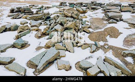 Grandi rocce e pietre raccolte in una cava di roccia con neve che si scioglie sui lati che saranno utilizzati per paesaggio paesaggistico. Foto Stock