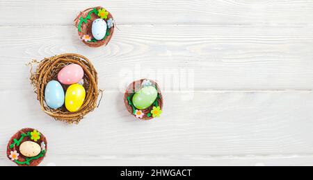 Uova di pasqua coloseful in nido su sfondo rosa con spazio. Concetto minimo. Scheda con spazio per la copia del testo. Foto Stock