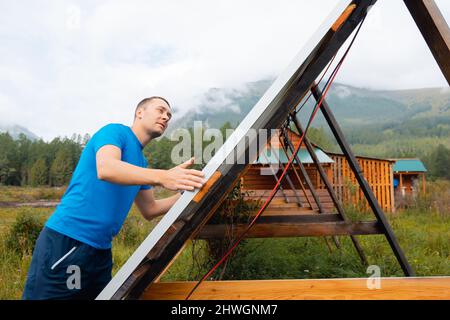 Giovane ingegnere maschio installazione e funzionamento pannelli solari. Concetto di preparazione degli elementi elettrici energetici per l'inverno. Foto Stock