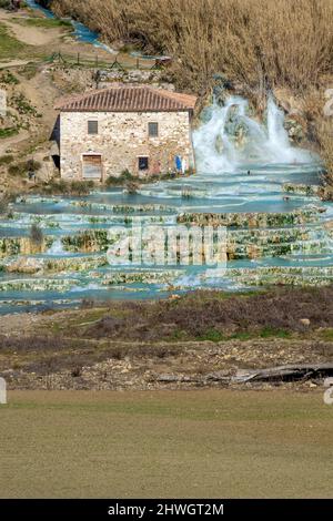 Le splendide sorgenti termali naturali di Saturnia Cascate del Mulino, Grosseto, Toscana, Italia, accanto ad un tipico casolare in pietra Foto Stock