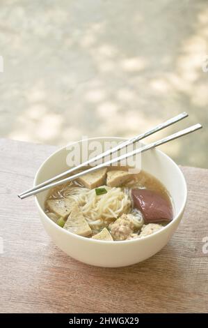 Spaghetti di riso vietnamiti o Pho con salsiccia a fette e tritare il maiale in zuppa su una ciotola Foto Stock
