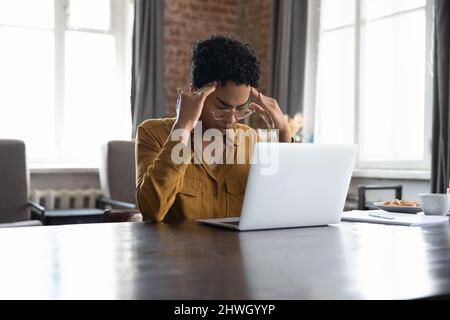 Stressata giovane donna freelance nera stanca che soffre di emicrania Foto Stock