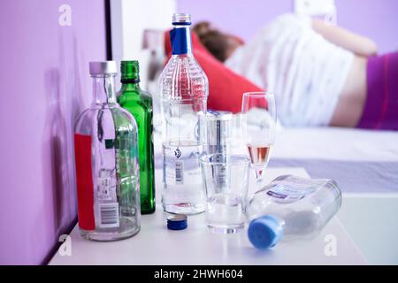 Rottweil, Germania. 04th Mar 2022. Illustrazione: Una ragazza adolescente si trova nel suo letto, mentre bottiglie di alcol e bicchieri sono posti sul suo comodino. (A dpa 'AK: I bambini depressivi abusano di sostanze addictive particolarmente spesso'). Credit: Silas Stein/dpa/Alamy Live News Foto Stock