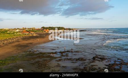 Le persone camminano lungo Echo Beach prima del tramonto. Scatto aereo di turisti godere del tempo prima del tramonto alla spiaggia popolare a Canggu sull'isola tropicale di Foto Stock