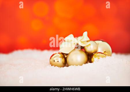Festivali. Studio girato di un arrangiamento di decorazioni dorate di Natale su uno sfondo rosso. Foto Stock