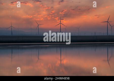 Turbine a vento all'alba con riflessione Foto Stock