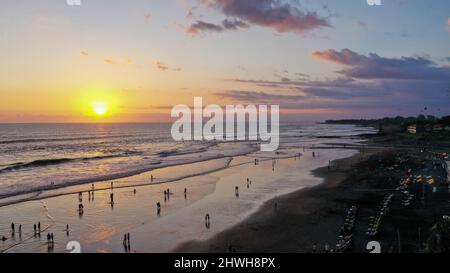 Le persone camminano lungo Echo Beach prima del tramonto. Scatto aereo di turisti godere del tempo prima del tramonto alla spiaggia popolare a Canggu sull'isola tropicale di Foto Stock