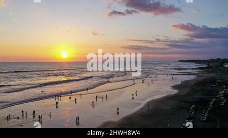 Le persone camminano lungo Echo Beach prima del tramonto. Scatto aereo di turisti godere del tempo prima del tramonto alla spiaggia popolare a Canggu sull'isola tropicale di Foto Stock