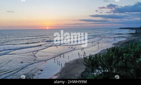 Le persone camminano lungo Echo Beach prima del tramonto. Scatto aereo di turisti godere del tempo prima del tramonto alla spiaggia popolare a Canggu sull'isola tropicale di Foto Stock