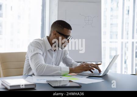 Concentrato il giovane imprenditore afroamericano che lavora al computer. Foto Stock