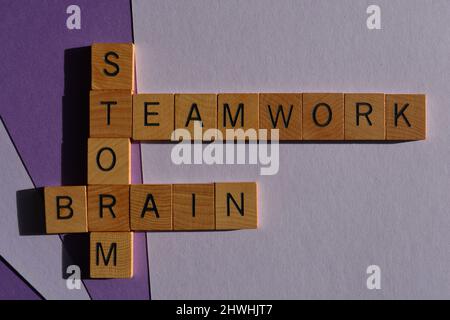 Lavoro di squadra, tempesta di cervello, parole in lettere in legno alfabeto in forma di parola incrociata isolato su sfondo viola Foto Stock
