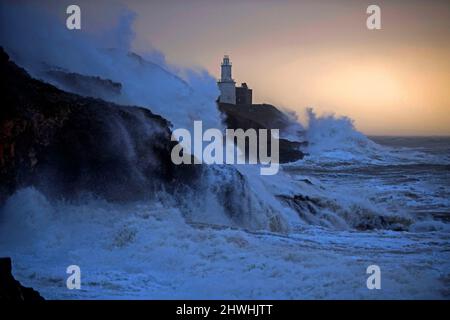 Le enormi onde si infrangono nella Mumbles Lighhouse sulla penisola di Gower, vicino a Swansea, in acqua alta, questa mattina, mentre la costa del Galles del Sud sente tutta la forza di Storm Eunice. Foto Stock