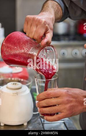 Servire succo di frutta con barbabietola da una caraffa di cristallo Foto Stock