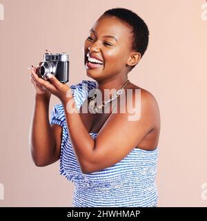 Una cattura, cento ragioni, mille ricordi. Studio girato di una bella giovane donna utilizzando una macchina fotografica contro uno sfondo di oink. Foto Stock