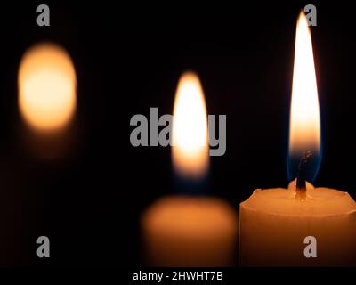 Immagine con sfondo nero due candele accese a destra con una sfocatura di luce a sinistra Foto Stock