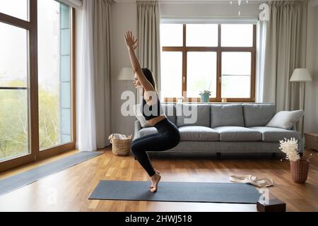 Donna sportiva e slim in abbigliamento sportivo nero in posa Utkatasana Foto Stock
