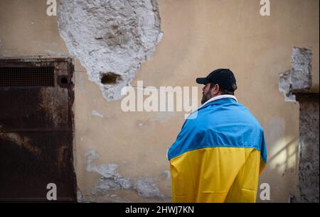 Protestante coperto di bandiera Ucraina blu e gialla che protestano contro la guerra in Ucraina per strada Foto Stock